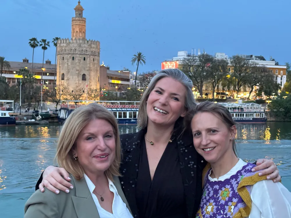 Tres compañeras de las corredurías de Mediavanz junto al Guadalquivir, con la Torre del Oro al fondo